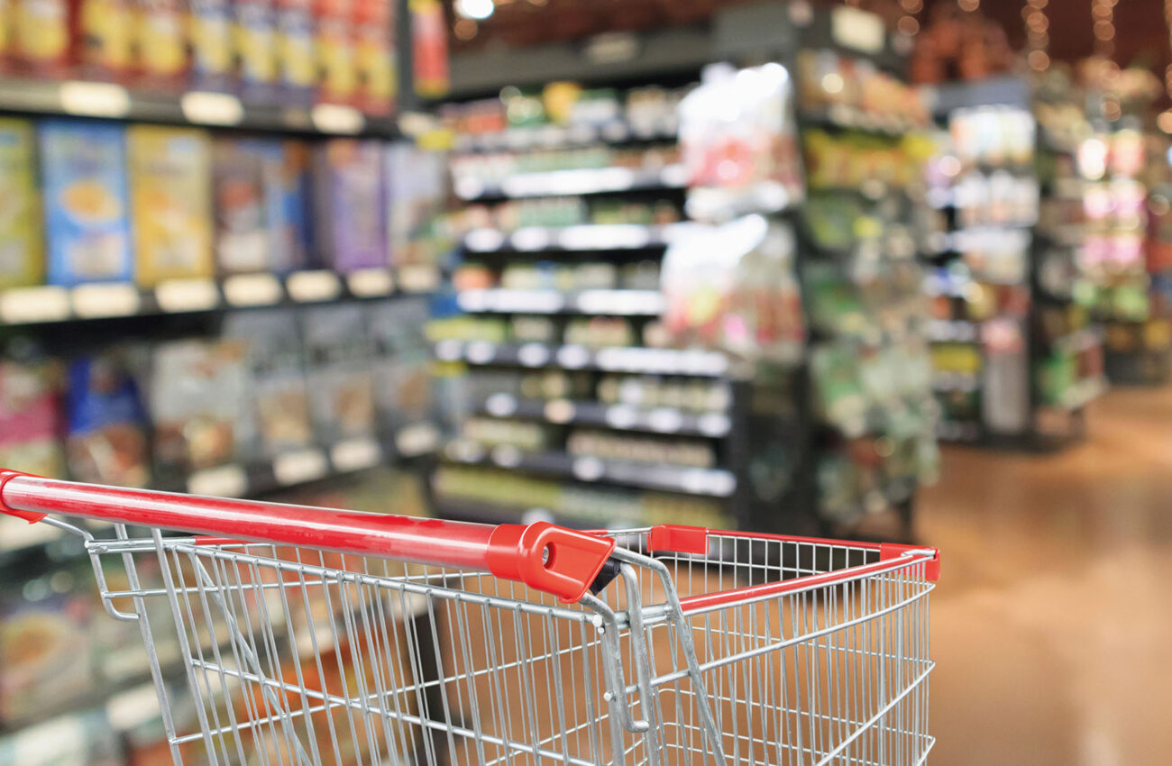 Supermarket aisle blurred background with empty red shopping car